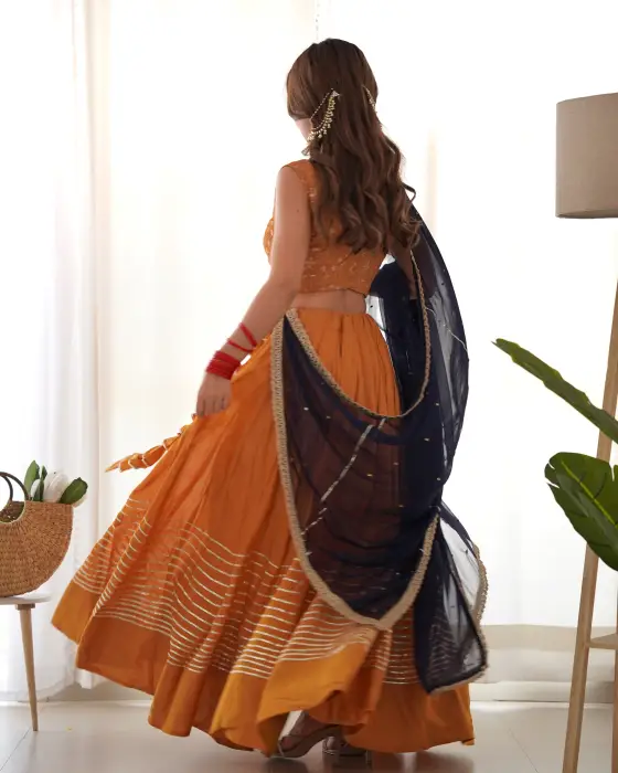 THE DANDELION MUSTARD LEHENGA SET WITH THE DETAILING OF PANI COLOUR GOTA IT’S A FULL FLARED LEHENGA COMES ALONG WITH GEORGETTE EMBROIDERED BLOUSE AND NAVY BLUE CHIFFON DUPATTA DETAILING OF LACE .The colors seen in the image may vary from the actual produc